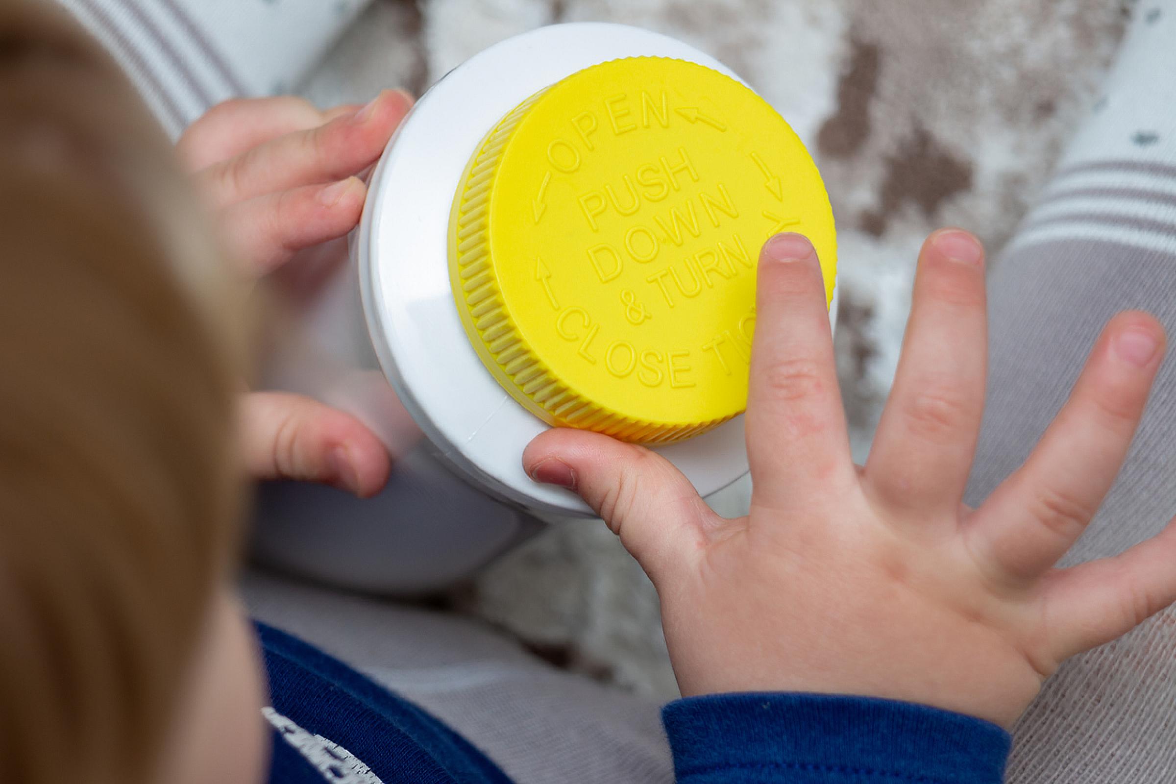 Child holding child-resistant packaging bottle