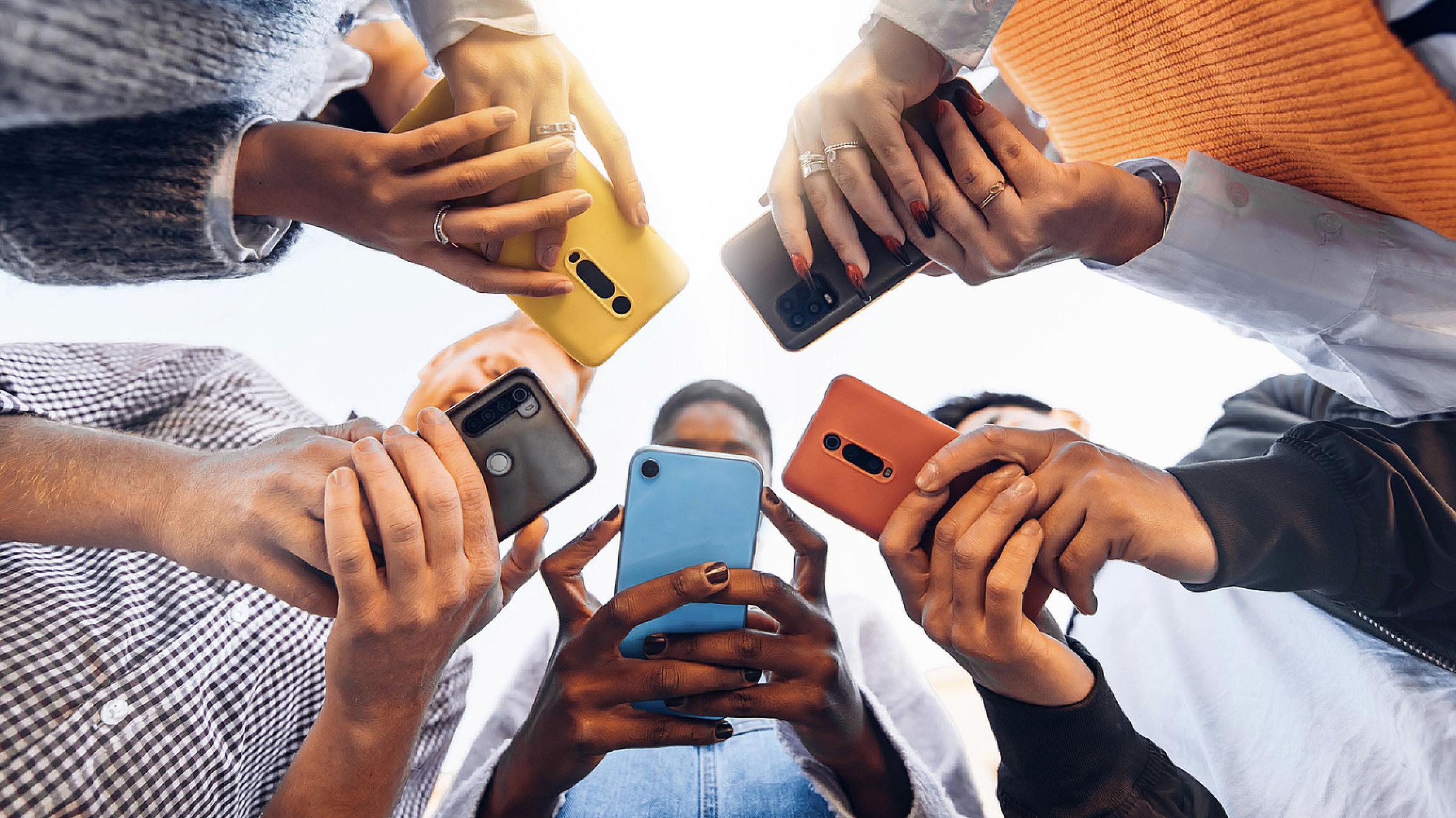 Teens in circle holding smart phones